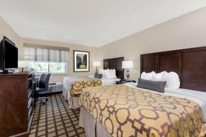a hotel room with two beds and a flat screen tv at Baymont by Wyndham Erie in Erie +47 photos