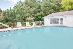 a swimming pool with chairs and a house at Baymont by Wyndham Ozark in Ozark