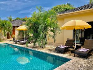 a pool with chairs and umbrellas next to a house at Amber Villas Diani in Diani Beach