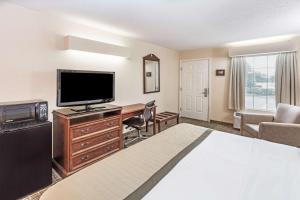 a hotel room with a bed and a flat screen tv at Baymont by Wyndham Valdosta at Valdosta Mall in Valdosta