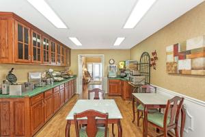 a kitchen with wooden cabinets and a table and chairs at Baymont by Wyndham Valdosta at Valdosta Mall in Valdosta