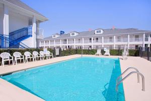 a swimming pool in front of a large house at Baymont by Wyndham Forest City in Forest City