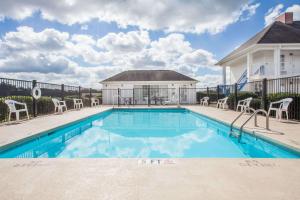 a swimming pool with chairs and a house at Baymont by Wyndham Hickory in Hickory