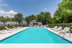 a swimming pool with chaise lounges and chairs at Baymont by Wyndham Anderson Clemson in Anderson