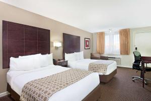 a hotel room with two beds and a desk at Baymont by Wyndham Sandusky in Sandusky +32 photos