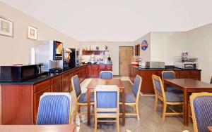a restaurant with a table and chairs and a kitchen at Baymont by Wyndham Battle Creek Downtown in Battle Creek