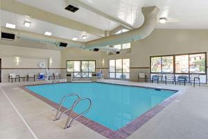 a large swimming pool in a building with tables and chairs at Baymont by Wyndham Provo River in Provo