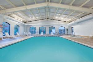 a large pool with blue water in a room with windows at Baymont by Wyndham Bartonsville Poconos in Bartonsville