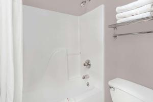 a white bath tub sitting next to a white toilet at Baymont Inn & Suites by Wyndham San Marcos in San Marcos