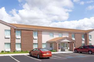 Un edificio con un coche rojo estacionado en un estacionamiento. en Baymont by Wyndham Beloit, en Beloit