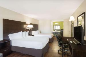 a hotel room with two beds and a desk and a television at Baymont by Wyndham Modesto Salida in Modesto