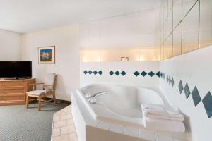 biała łazienka z wanną i telewizorem w obiekcie Baymont by Wyndham Hot Springs w mieście Hot Springs