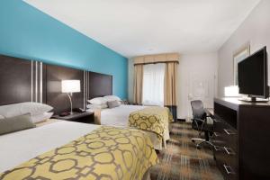 a hotel room with two beds and a flat screen tv at Baymont by Wyndham Bryan College Station in Bryan
