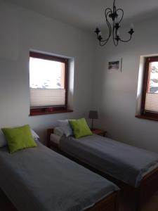 twee bedden in een kamer met twee ramen bij Apartament Słoneczny 6 Kościelisko in Kościelisko