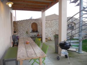 a patio with a wooden table and chairs and a grill at Chambre d'hôte Fleur de Potager in Les Sables-dʼOlonne