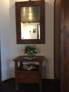 una mesa con un espejo y un jarrón con flores. en Stefanina Guesthouse, en Bozhentsi