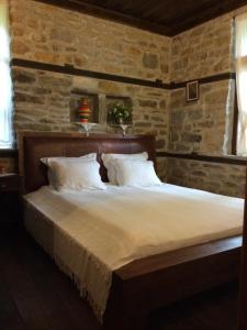 a bed in a room with a stone wall at Stefanina Guesthouse in Bozhentsi