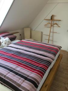 uma cama com um cobertor listrado colorido num sótão em Alte Schreinerei em Veringendorf