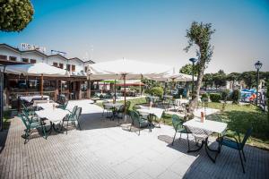 un patio extérieur avec des tables, des chaises et des parasols dans l'établissement Hotel Johnson, à Peschiera del Garda