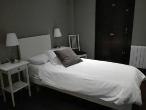 Un dormitorio con una gran cama blanca y una mesita de noche. en Casa Rural Kutxatxuri, en Aracaldo