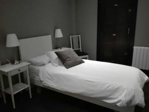 1 dormitorio con 1 cama blanca grande y mesita de noche en Casa Rural Kutxatxuri, en Aracaldo