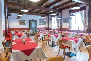 a dining room with red and white tables and chairs at Hotel Schwabenwirt in Berchtesgaden