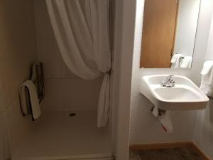 a bathroom with a sink and a shower with a shower curtain at Howard's Motel in Glendo