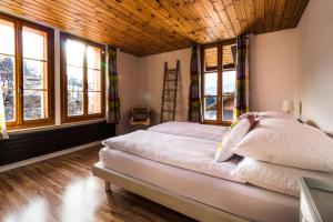 Schlafzimmer mit einem Bett mit Holzdecke und Fenstern in der Unterkunft Ula's Holiday Apartments in Beatenberg