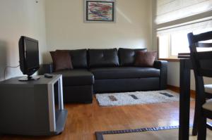 un soggiorno con divano nero e TV di Life in Porto Apartment by JC a Porto