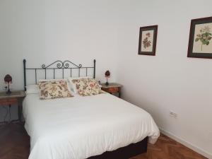 Apartamento Soho-Colón, ubicado en centro histórico في مالقة: غرفة نوم مع سرير مع شراشف بيضاء وطاولتين