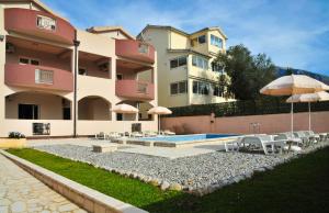 a large building with a swimming pool and umbrellas at Apartmani Bulajic in Tivat