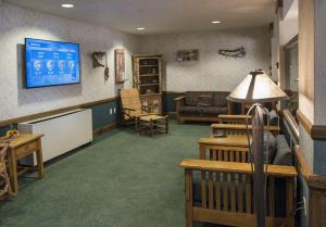 a waiting room with a couch and a tv at Potawatomi Inn & Cabins in Angola