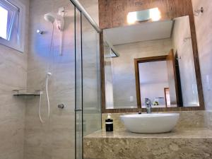 uma casa de banho com um lavatório e uma cabina de duche em vidro. em Apartamento no Centro de Gramado em Gramado