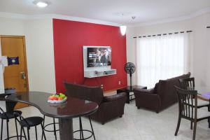 sala de estar con mesa y pared roja en Apartamento em Meia Praia, en Meia Praia