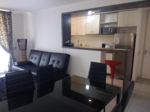 sala de estar con sofá negro y silla roja en Departamento arica, en Arica