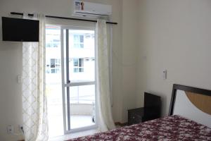 1 dormitorio con cama y ventana grande en Apartamento em Meia Praia, en Meia Praia