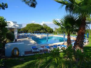 una gran piscina con sillas azules y palmeras en THE LAKERS Boutique Apartment, en Quinta do Lago