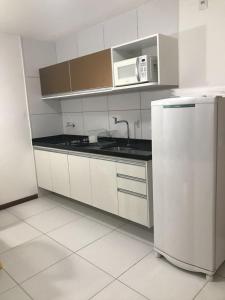 uma cozinha branca com um frigorífico e um micro-ondas em Residence Iloa Resort em Barra de São Miguel