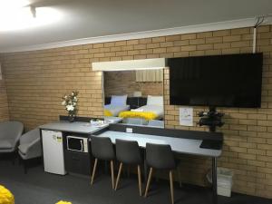 
a kitchen with a table, chairs and a television at Blue Violet Motor Inn in Toowoomba
