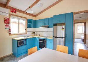 a kitchen with blue cabinets and a table with chairs at Toowoon Bay Holiday Park in The Entrance