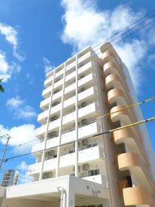 Hotel Peacely In Miyakojima Nexus في جزيرة مياكو: مبنى شقق بيضاء مقابل السماء الزرقاء