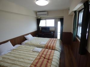 宮古島にあるホテルピースリーイン宮古島 NEXUSのベッド2台とテレビが備わるホテルルームです。