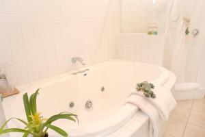 a white bath tub sitting next to a white toilet at Gecko Lodge Kalbarri in Kalbarri