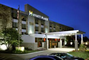 Hyatt Place Milwaukee Airport في ميلووكي: مبنى فندق فيه سيارات تقف امامه