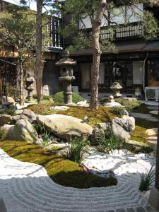 un jardin japonais avec une fontaine et des rochers dans l'établissement ShikiShiki Shinra, à Kyoto