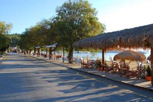 a beach with tables and chairs and straw umbrellas at koula's apartments in Vasiliká