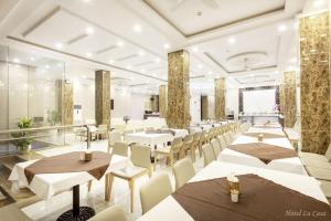 a restaurant with white tables and white chairs at La Casa Hotel Nha Trang in Nha Trang