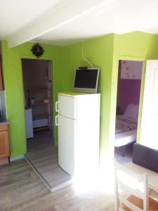 ヴァルラ・プラージュにあるcoquet appartement valras plageの緑の壁の客室で、テレビ、ベッドが備わります。