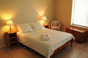 a bedroom with a bed with two shoes on it at Kian's Place Holiday Home in Langebaan
