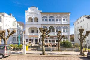 ein weißes Gebäude mit Bäumen davor in der Unterkunft MyHome Ruegen - Haus Johanneshorst in Ostseebad Sellin